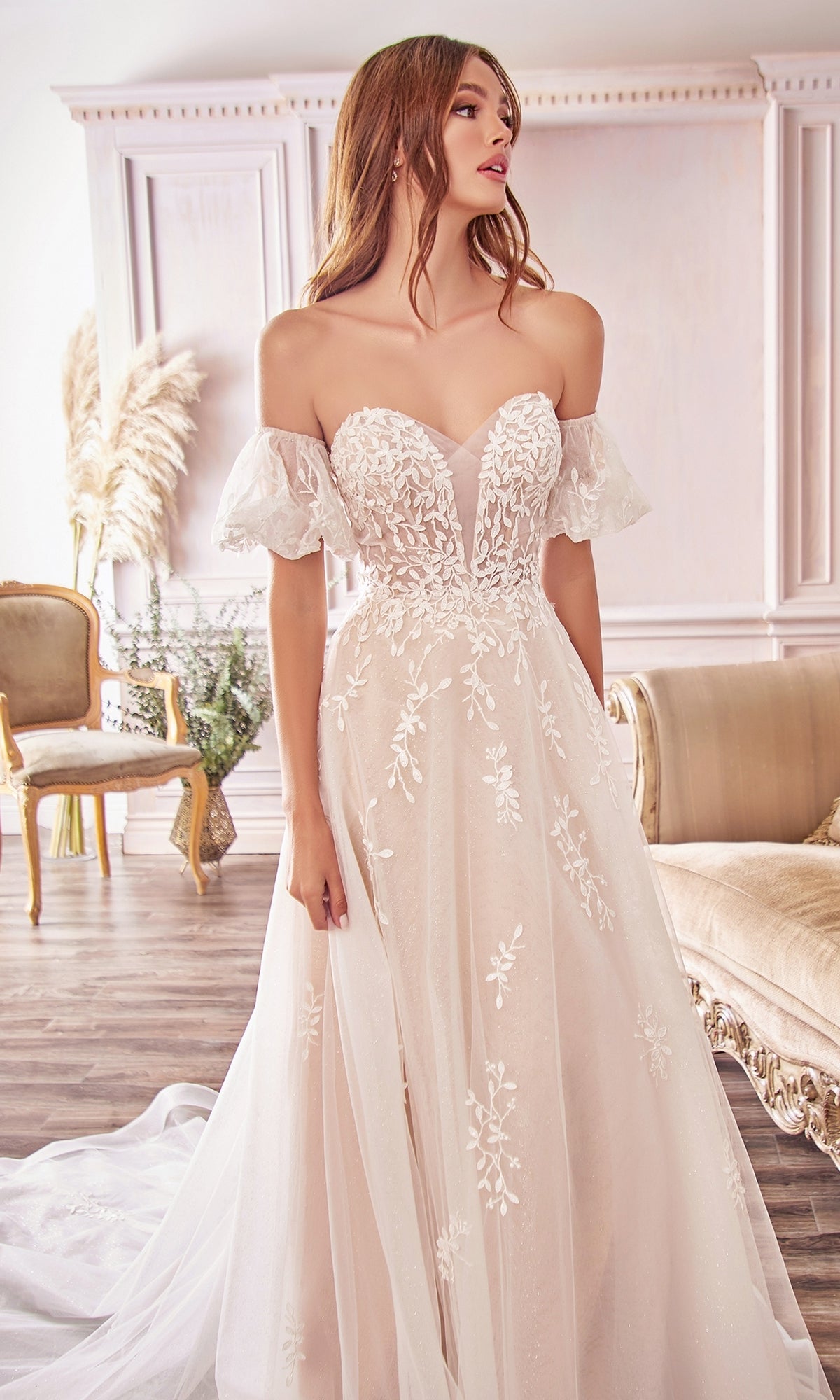 A woman wearing the Puff-Sleeve Long White Wedding Dress A1014, featuring lace embroidery and removable puff sleeves, stands in an elegant room with classic décor and neutral furniture.